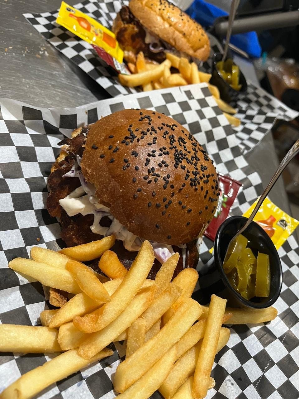 BirriaBurguer con pan de ajonjolí negro, papas a la francesa y chiles en vinagre